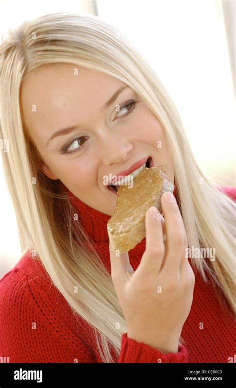 Female Long Blonde Straight Hair Wearing Red Polo Neck Jumper And Red Lipstick Holding Piece Of