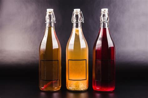 Tres Botellas Con Bebidas De Diferentes Colores Sobre Un Fondo Negro