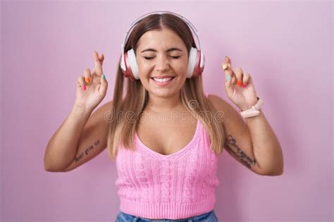Jeune Femme Blonde écoutant De La Musique Avec Un Casque Gesturant Doigt Croisé Souriant Avec