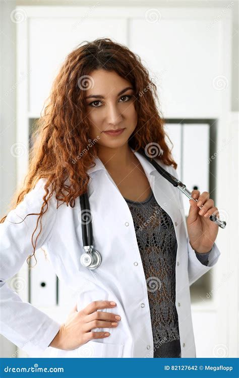 Beautiful Smiling Female Doctor Stand In Office Holding Stethoscope