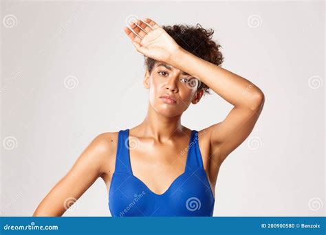 Close Up Of Tired Young Female Athlete In Sportswear Wiping Sweat Off