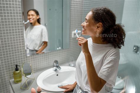 Beautiful Woman Brushing Teeth In Front Of Her Bathroom Mirror Morning