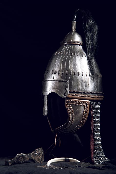 a helmet with long black hair is shown on the ground next to an open book