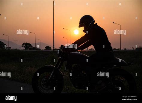 Silhouette Of Man Riding Vintage Motorcycle Cafe Racer Style With