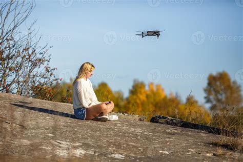 girl controls a drone sitting on high rock in the mountains 14963132 Stock Photo at Vecteezy