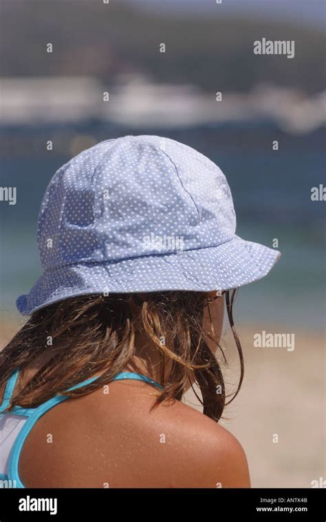 Young girl on beach wearing sun hat to protect head from sun on sunny ...