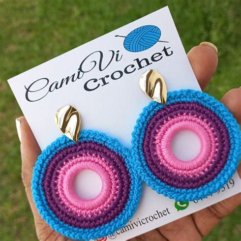 A Pair Of Pink And Blue Crochet Earrings On Top Of A White Card