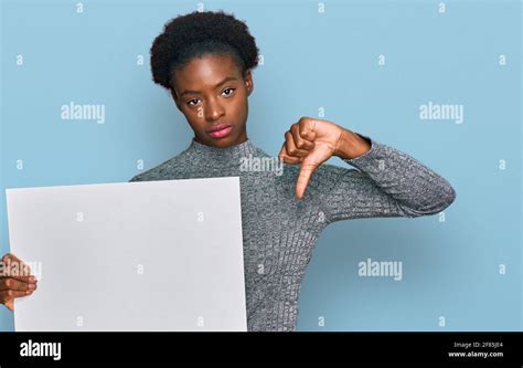 Young African American Girl Holding Blank Empty Banner With Angry Face Negative Sign Showing