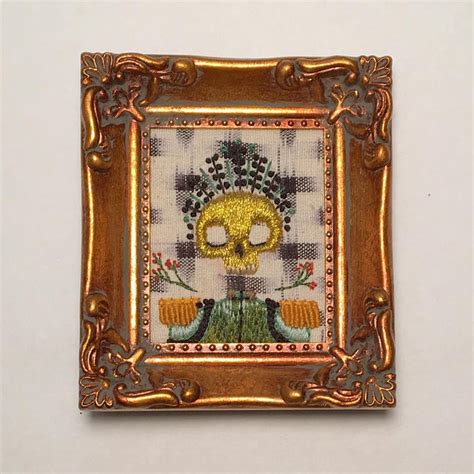 A Cross Stitch Picture Frame With A Skull On It S Face And Flowers In