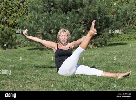 Front View Of Flexible Blonde Senior Woman Is Stretching Exercising Outdoors The Smiling Woman