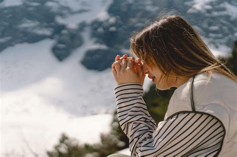 Mujer cerró los ojos rezando cerca de la montaña manos dobladas en