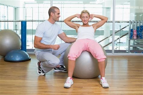 Premium Photo Male Trainer Assisting Woman With Abdominal Crunches At Gym