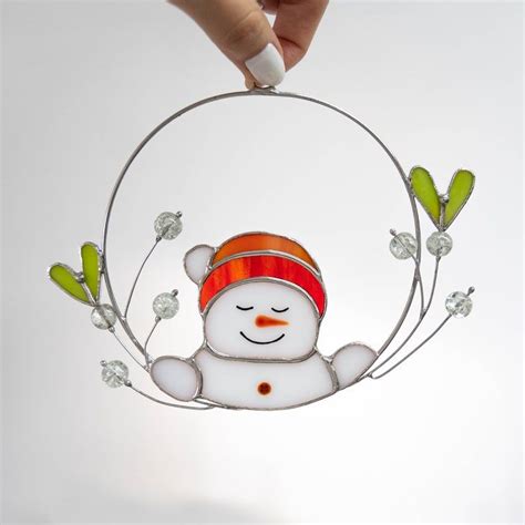 A Hand Is Holding A Glass Ornament With A Snowman In The Middle