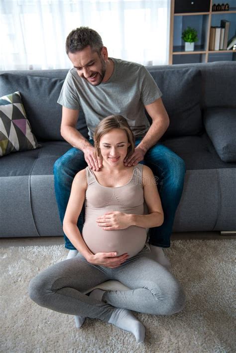 Marido Cuidadoso Que Da Masajes A Hombros De La Mujer Embarazada Imagen