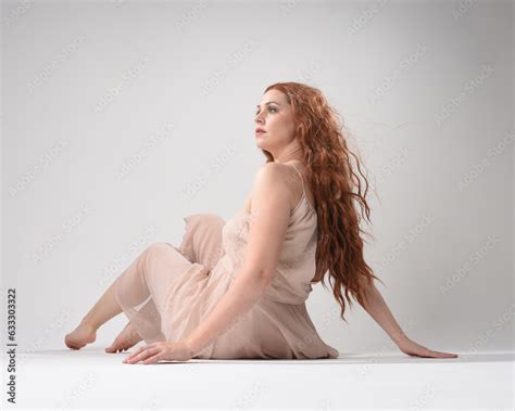 Full Length Portrait Of Beautiful Brunette Model Wearing A Pink Dress Graceful Sitting Pose