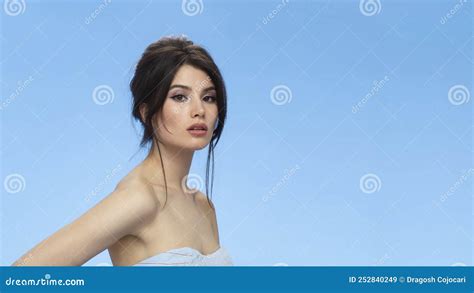 Beauty Image Of A Cute Brunette With Bare Shoulders With Makeup And Hairstyle Over Blue