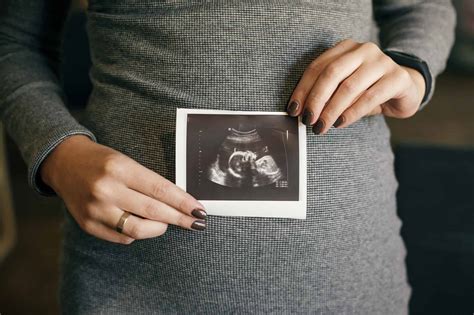 Stylish Pregnant Woman Holding Ultrasound Scan Of Her Baby On Her Baby