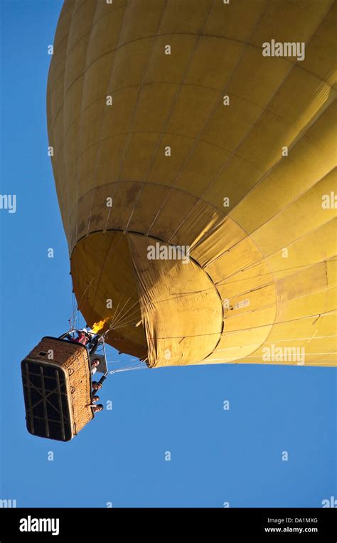 Vertical View Of A Yellow Hot Air Balloon In Flight With Passengers