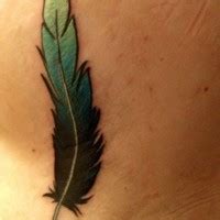 Great Blurred Colorful Feather Tattoo On Thigh Tattooimages Biz