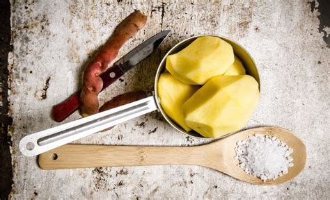 Premium Photo The Peeled Potatoes In A Metal Saucepan With A Spoonful