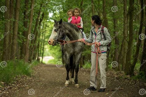 Girls Enjoying Horseback Riding In The Woods With Mother Young Pretty