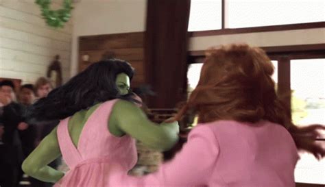 A Woman In A Pink Dress Is Dancing With A Green Monster On Her Back And