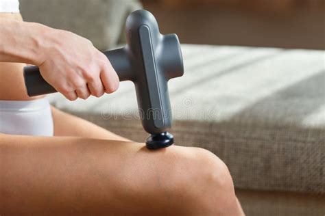 Self Massage Of Womenand X27 S Legs With A Perfecting Gun At Home Stock