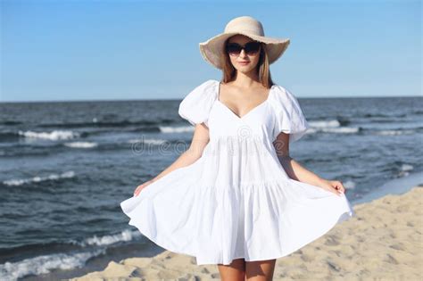 Happy Smiling Blonde Woman Is Posing On The Ocean Beach With Sunglasses And A Hat Stock Image