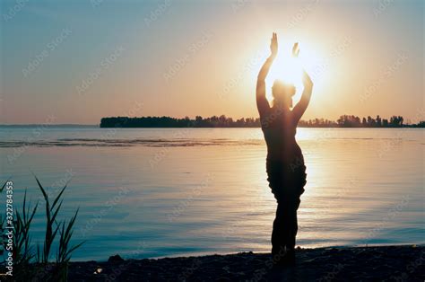 Dark Glowing Silhouette Of Slim Woman With Hands Up In The Air