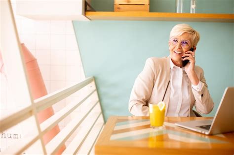 Mulher S Nior Usando Telefone Celular Enquanto Trabalhava No Laptop E