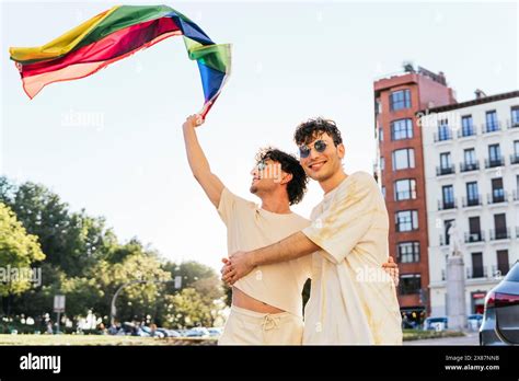 Carefree Gay Couple Waving Rainbow Flag At Gay Pride Parade Stock Photo Alamy