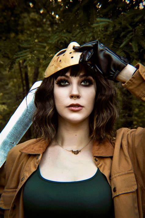 A Woman Wearing A Helmet And Holding A Knife Over Her Head With Trees