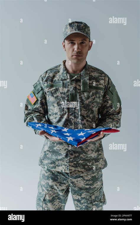 American soldier in uniform holding folded flag of United States during memorial day isolated on ...