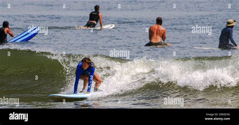 Gilgo Beach, New York, USA - 22 July 2023: Women surfing in a blue long ...