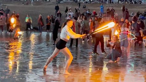 Poi fire performers practice at beach during sunset