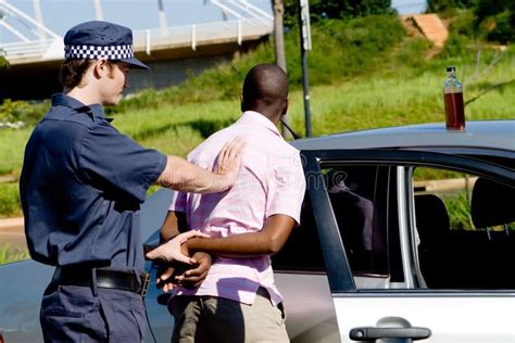 Two Men Standing Next To Each Other Near A Police Car And One Is Holding The Door Open