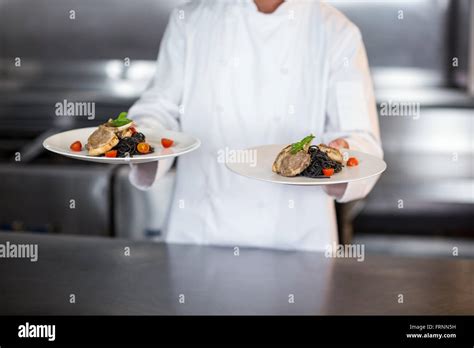 Midsection Of Chef Holding Plates In Kitchen Stock Photo Alamy