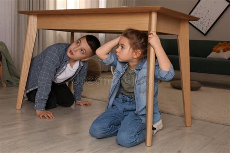 Niños Asustados Escondiéndose Debajo De La Mesa En La Sala De Estar