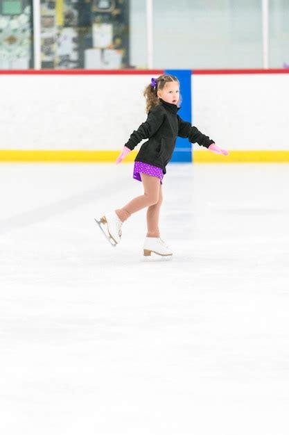 Menina praticando patinação artística em uma pista de patinação no gelo