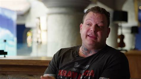 a man with tattoos sitting in a restaurant