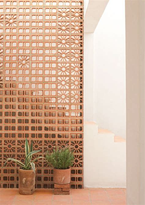 Two Potted Plants Are Sitting On The Floor In Front Of A Latticed Wall