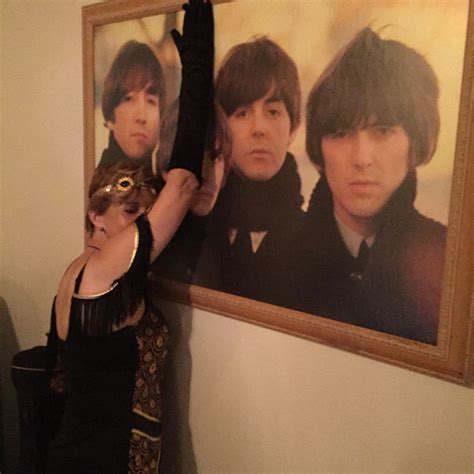 A Woman Standing In Front Of A Wall With An Image Of The Beatles On It