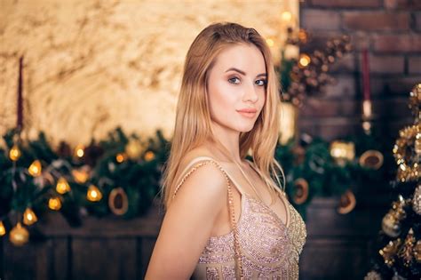 Portrait d une femme blonde luxueuse en robe de soirée dorée sur fond de sapin de Noël et de