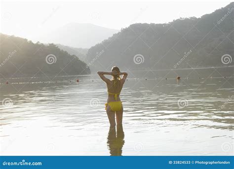 Mujer En El Bikini Amarillo Que Se Coloca En El Lago Imagen De Archivo