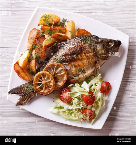 Grilled Fish With Fried Potatoes And Salad On A Plate Top View Closeup