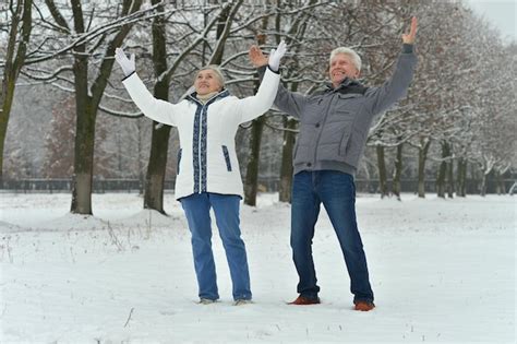 Premium Photo Happy Senior Couple At Snowy Winter Park With Hands Up