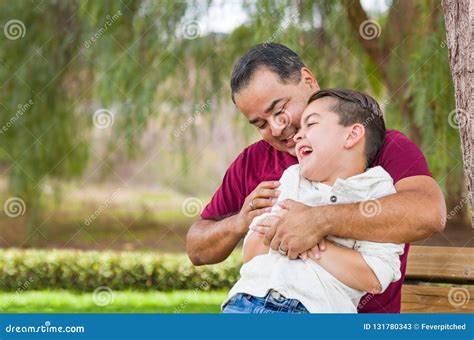 Mixed Race Hispanic Father Tickling His Son At The Park Stock Image