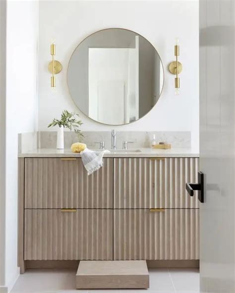 A Greige Fluted Vanity With Gold Handles A Stone Countertop A Round