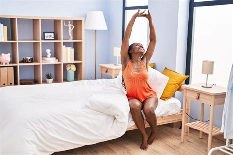 African American Woman Waking Up Stretching Arms At Bedroom Stock Image