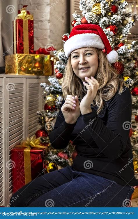 A Blonde Woman In A Santa Hat Is Sitting By The Christmas Tree New Year S Eve Celebration Stock